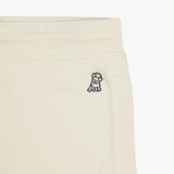 Close-up of the embroidered dog logo on the cream-colored jogger pants