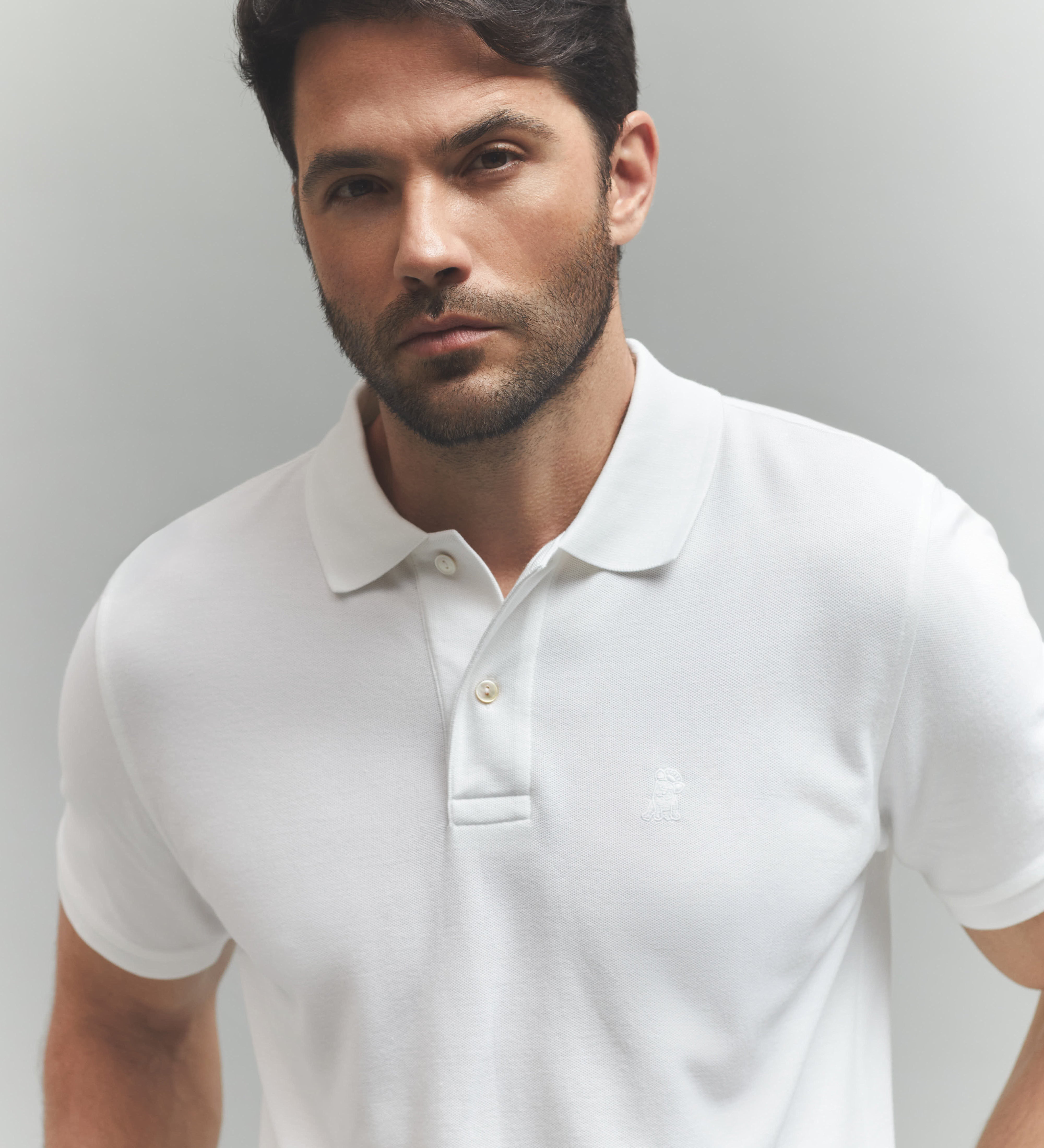 Man wearing a white polo shirt against a plain background