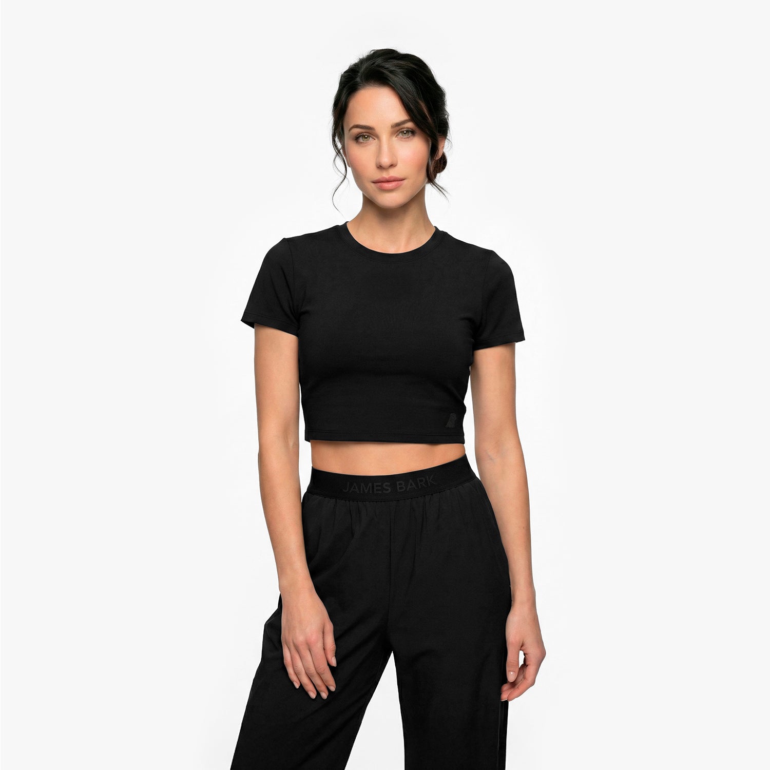 Woman wearing a black crop top and black pants on a white background
