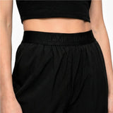 Black athletic pants with 'JAMES BARK' waistband on a neutral background