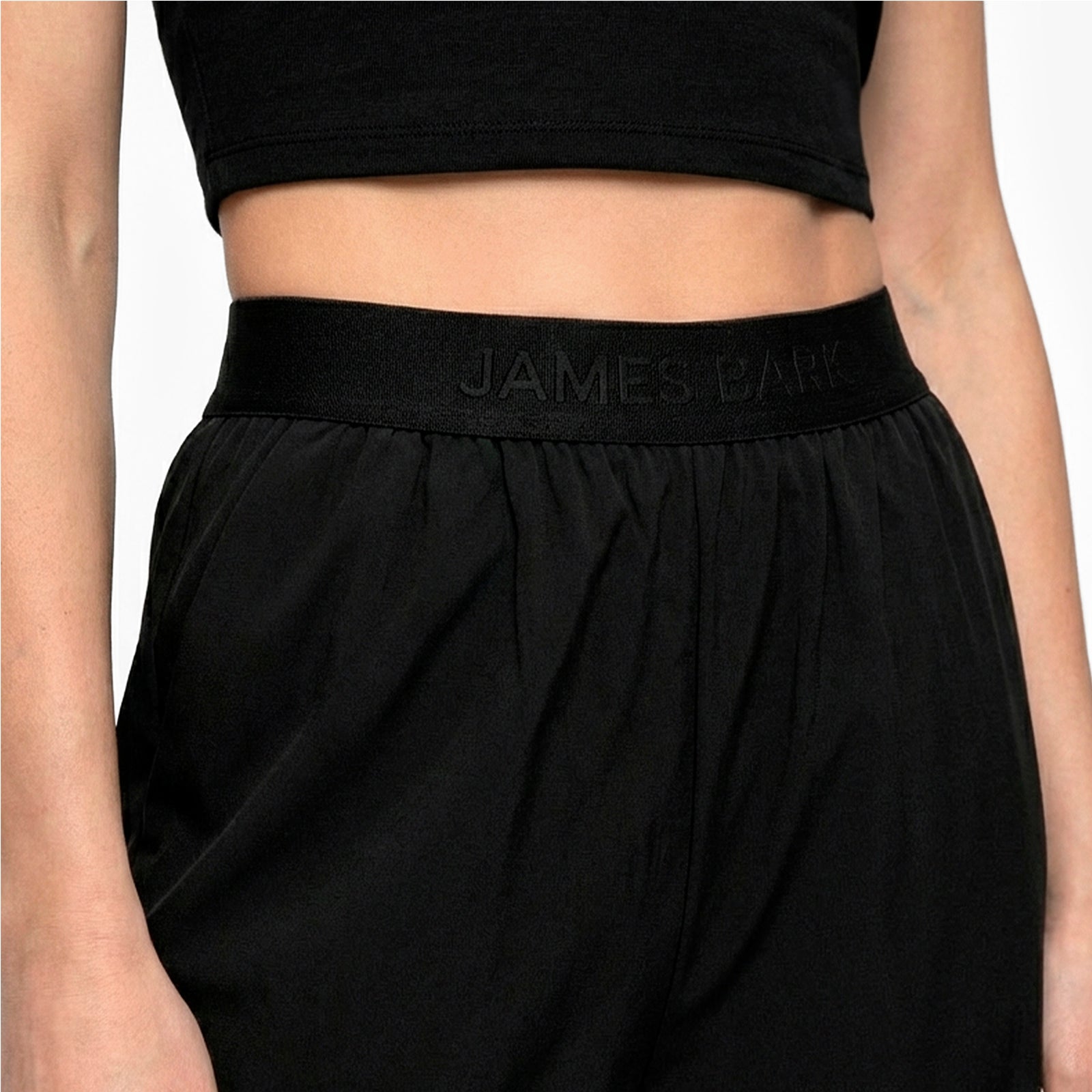 Black athletic pants with 'JAMES BARK' waistband on a neutral background