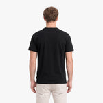 Man wearing a black t-shirt and light-colored pants on a white background