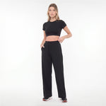 Woman wearing a black crop top and black pants on a white background