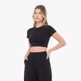 Woman wearing a black crop top and black pants on a white background