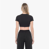 Person wearing a black crop top and black pants on a white background