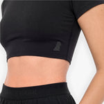 Person wearing a black athletic outfit with a visible brand logo on a light gray background