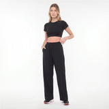 Woman wearing a black crop top and black pants on a white background