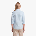 Woman wearing a light blue shirt and beige pants on a white background