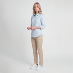 Woman wearing a light blue shirt and beige pants on a white background