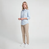 Woman wearing a light blue shirt and beige pants on a white background