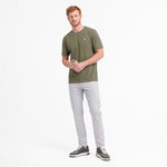 Man wearing a green t-shirt with gray pants on a white background