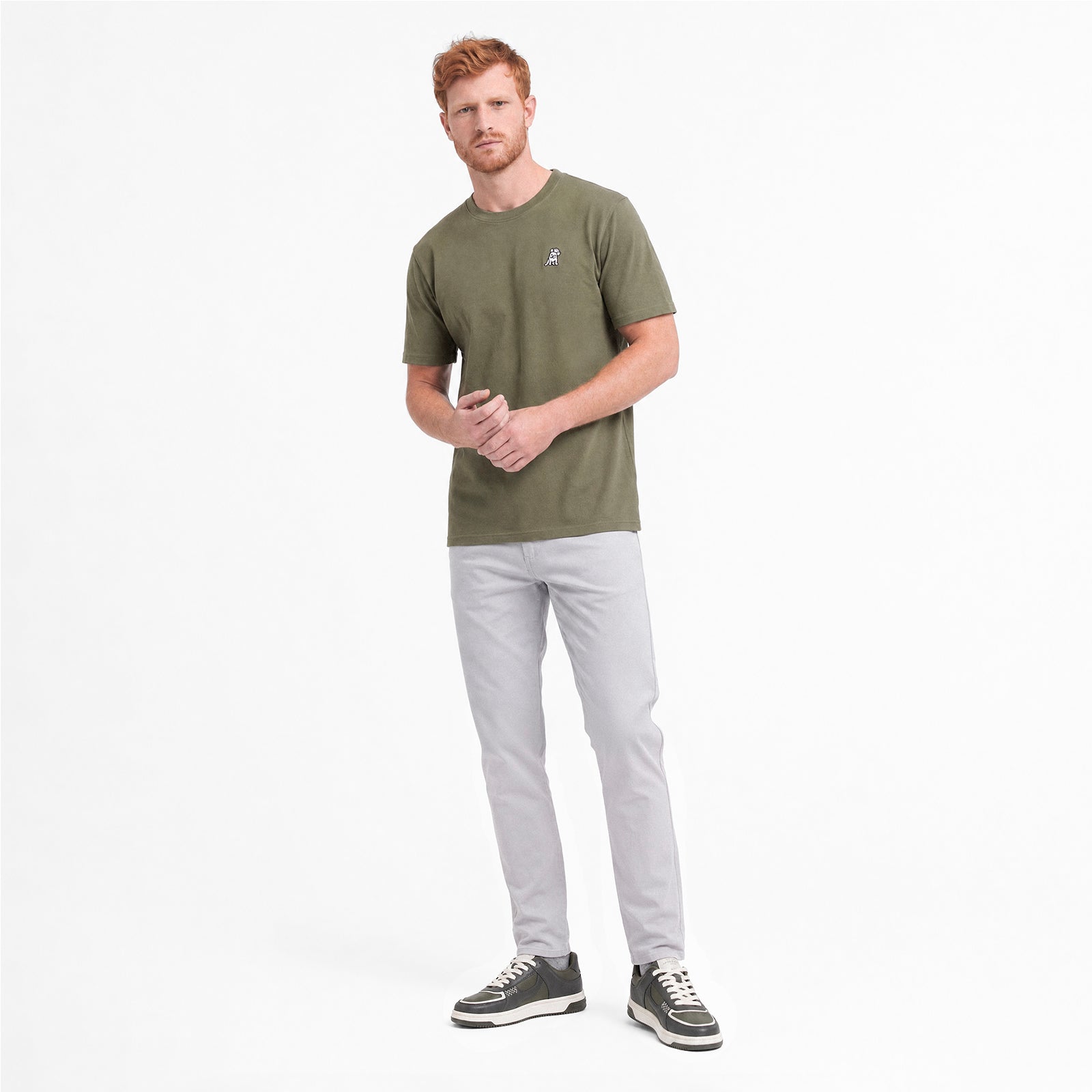Man wearing a green t-shirt with gray pants on a white background