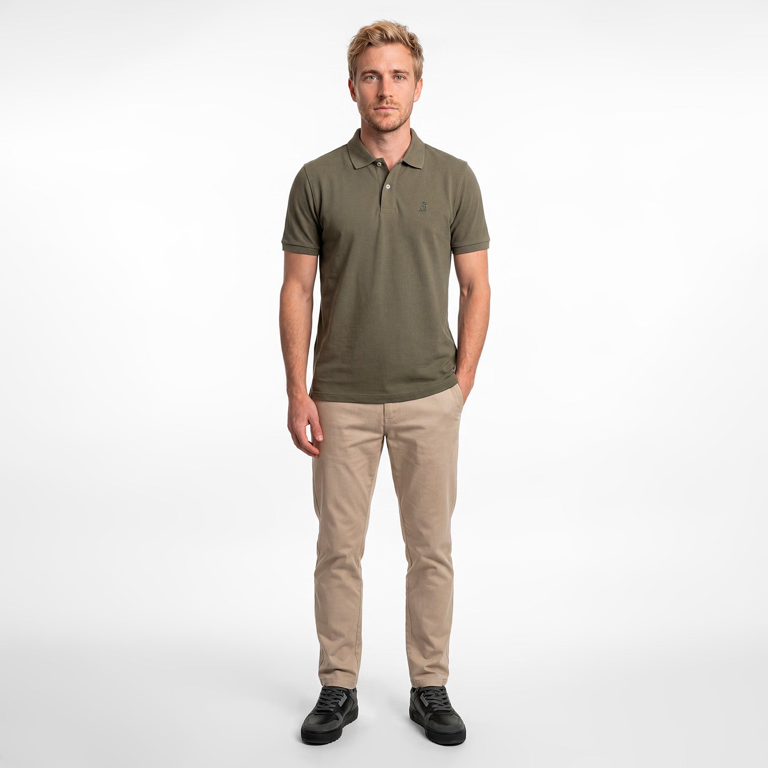 Man wearing a green polo shirt and beige pants on a white background