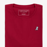 Close-up of the neckline of a red T-shirt, showing the small embroidered logo on the chest and internal tag.