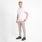 A man modeling a white short-sleeve crewneck t-shirt with a small black logo on the left chest, paired with gray trousers