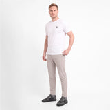 A man modeling a white short-sleeve crewneck t-shirt with a small black logo on the left chest, paired with gray trousers