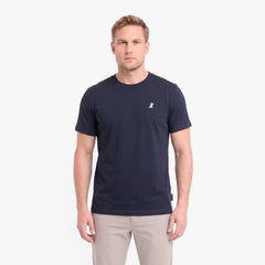 A man wearing a navy blue short-sleeve crewneck t-shirt with a small white embroidered logo