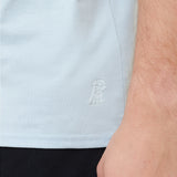 Light blue shirt with a logo on the chest worn by a person.