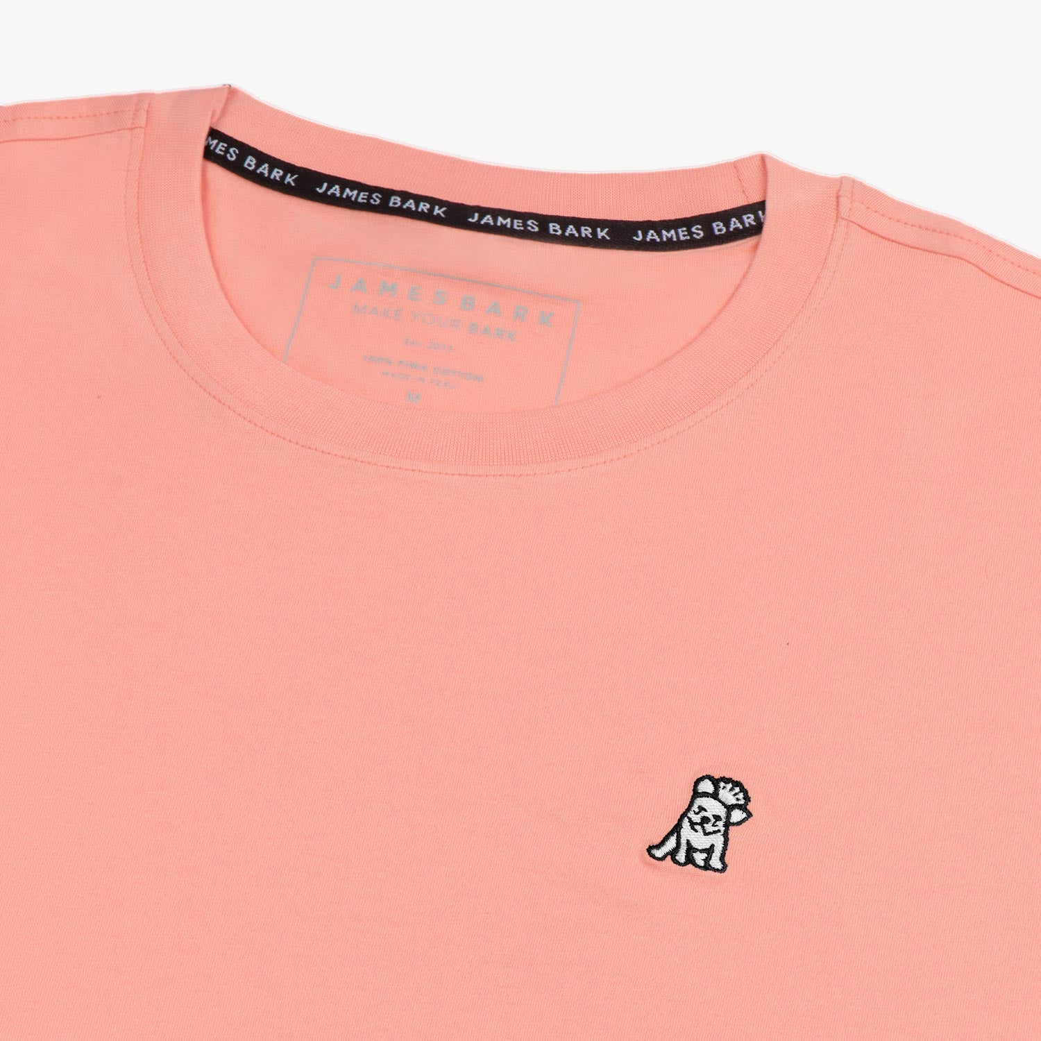 Close-up of the collar and inner label of the light pink t-shirt, showing the brand information and neck design.