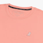 Close-up of the collar and inner label of the light pink t-shirt, showing the brand information and neck design.