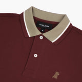 Side view close-up of the collar and chest of the maroon polo shirt: A detailed side profile showing the beige collar with white piping and the small embroidered dog logo on the left chest.