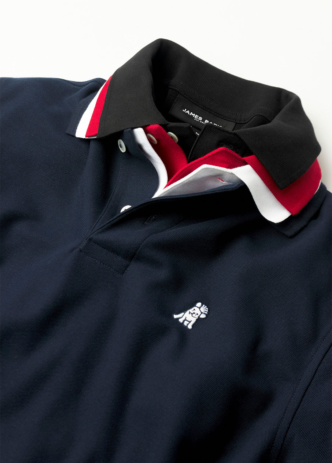 Close-up of a black polo with red and white accents on a white background
