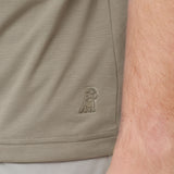 Close-up of beige shorts with a logo on the side, showing skin texture.