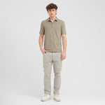 Man wearing a green polo shirt and light gray pants on a white background