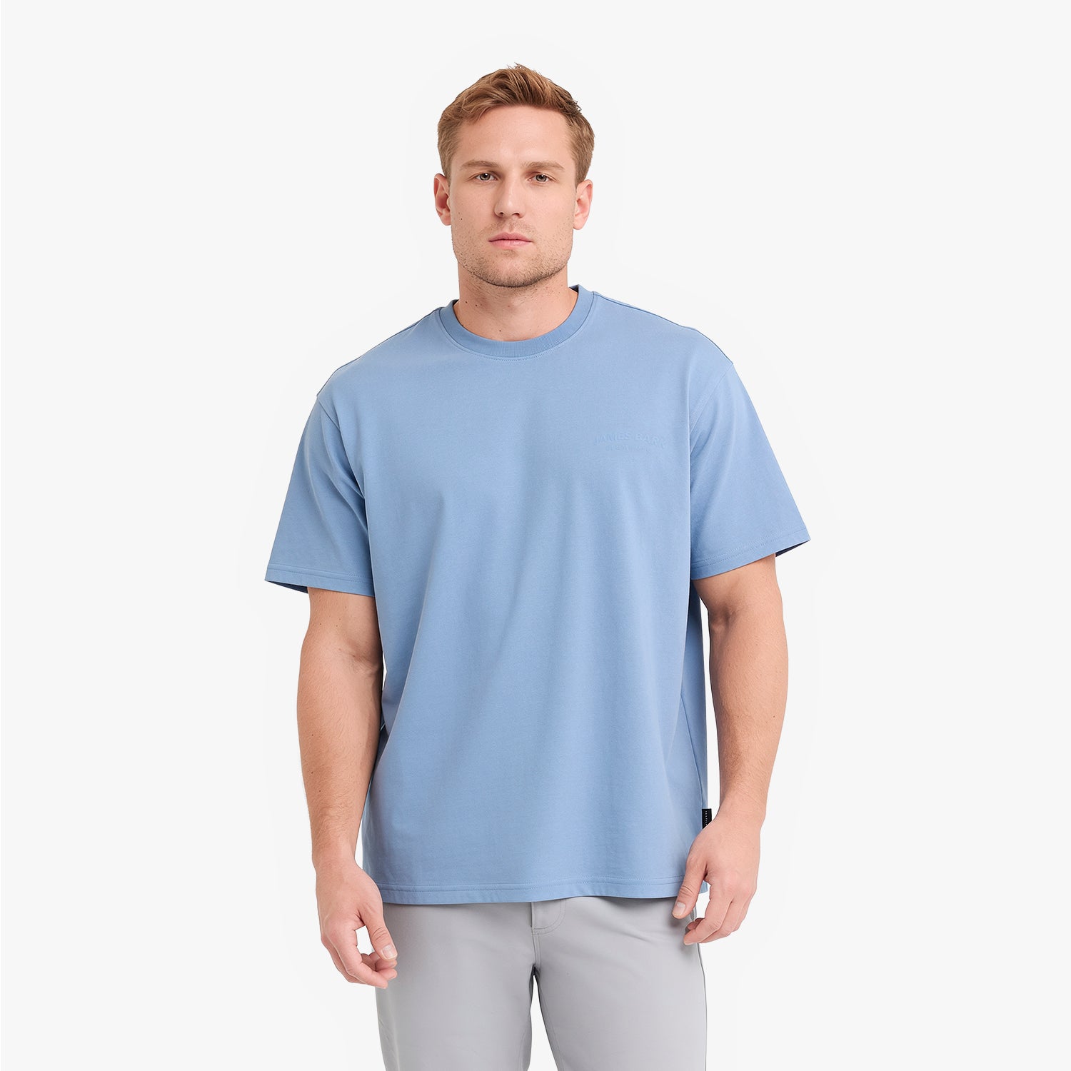 A man wearing a light blue crew-neck t-shirt and light gray pants