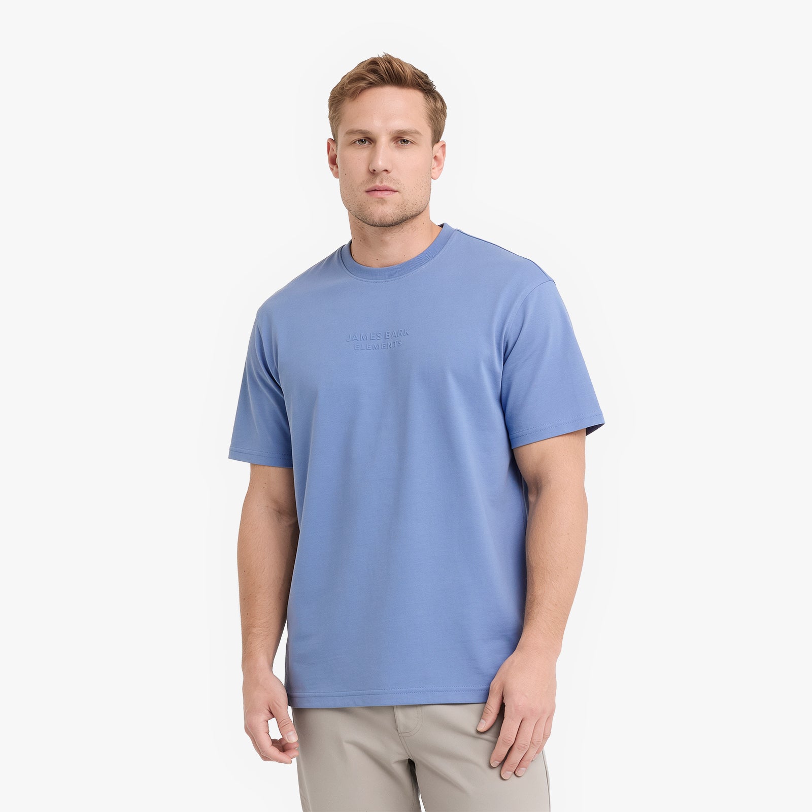 A man wearing a light blue crewneck t-shirt and beige pants