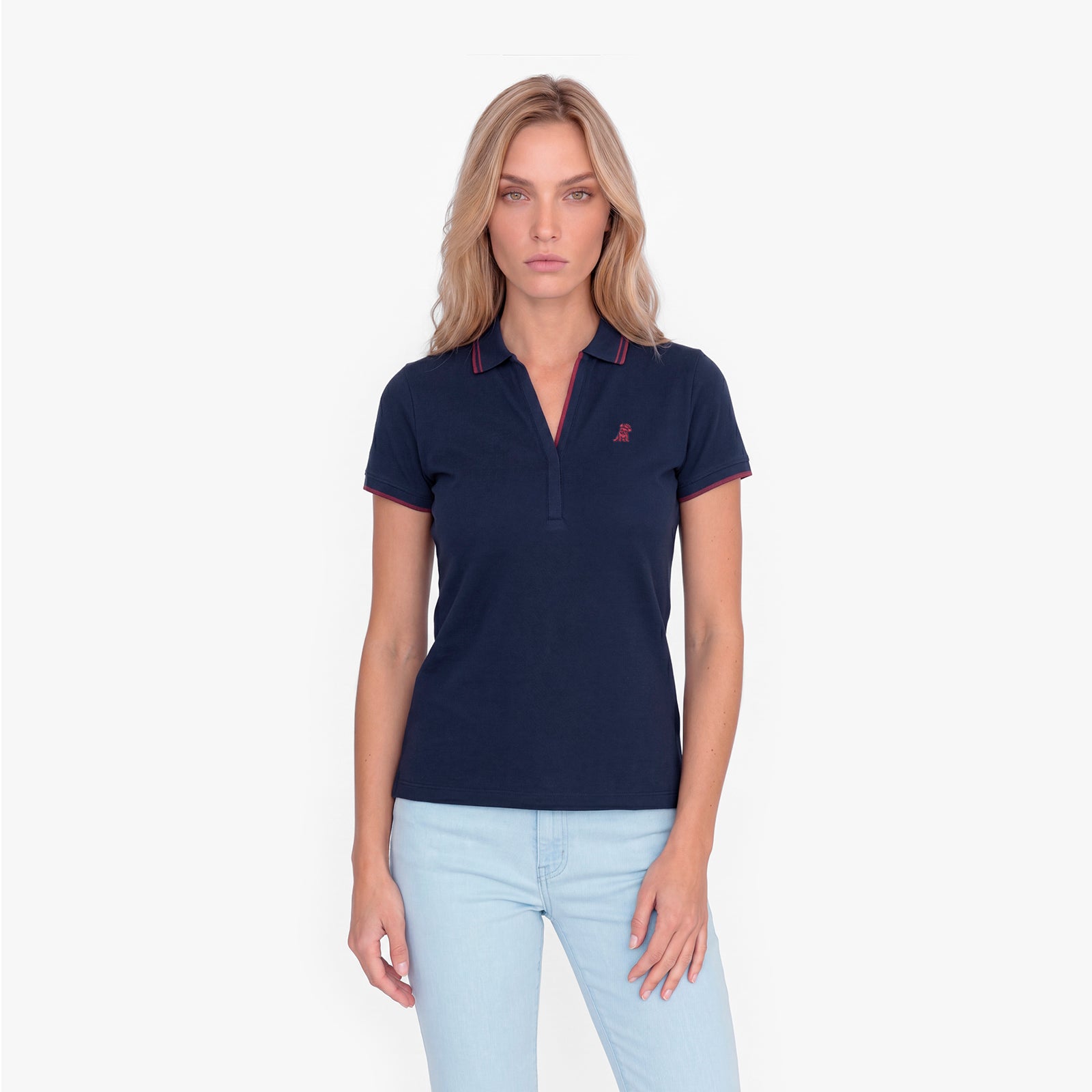 Woman wearing a navy polo with an embroidered dog logo on a white background