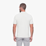 Man wearing a white polo shirt and light gray pants on a white background