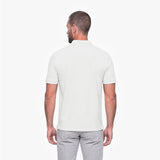 Man wearing a white polo shirt and light gray pants on a white background