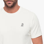 White t-shirt with a small logo on the chest worn by a person.