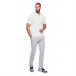 Man wearing a white polo shirt and gray pants on a white background