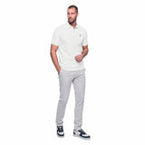 Man wearing a white polo shirt and gray pants on a white background