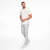 Man wearing a white t-shirt and gray pants on a white background