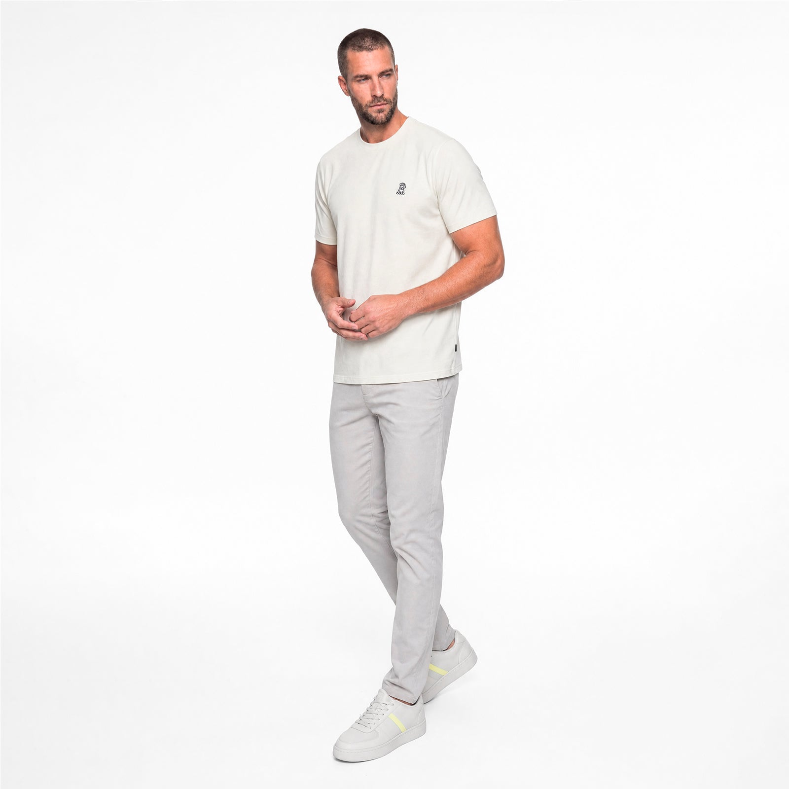 Man wearing a white t-shirt and gray pants on a white background