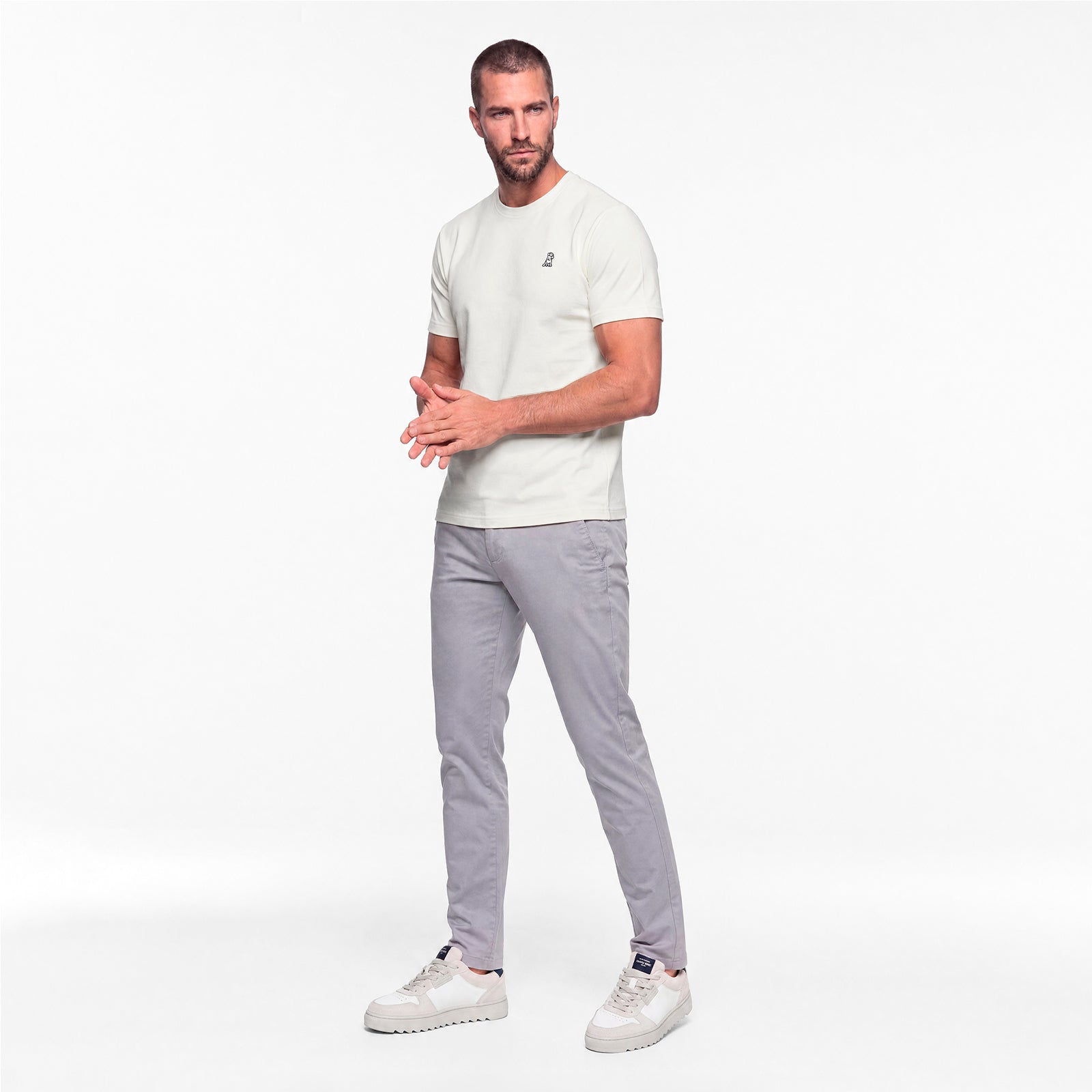 Man wearing a white t-shirt and gray pants on a white background
