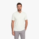 Man wearing a white polo shirt and gray pants on a white background