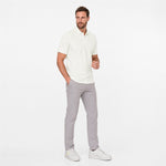 Man wearing a white polo shirt and gray pants on a white background