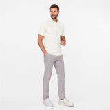 Man wearing a white polo shirt and gray pants on a white background