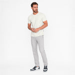 Man wearing a white t-shirt and gray pants on a white background