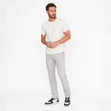 Man wearing a white t-shirt and gray pants on a white background
