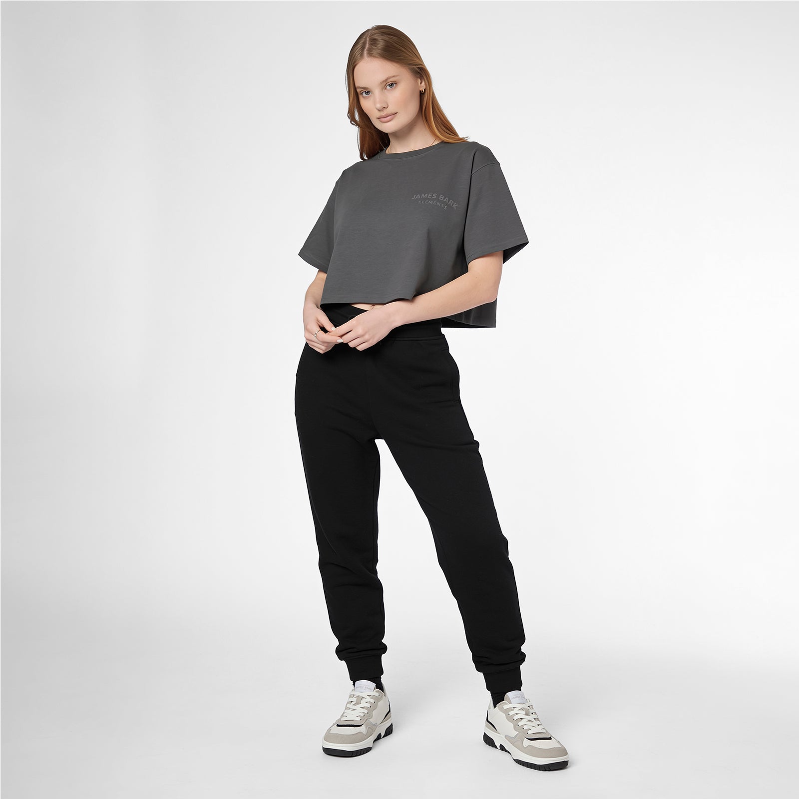 Full-length shot of a woman modeling a grey James Bark Elements cropped t-shirt and black joggers.