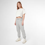 A woman modeling a white cropped T-shirt and light gray jogger sweatpants with white sneakers