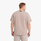 A man viewed from the back wearing a light beige short-sleeve t-shirt and matching beige pants