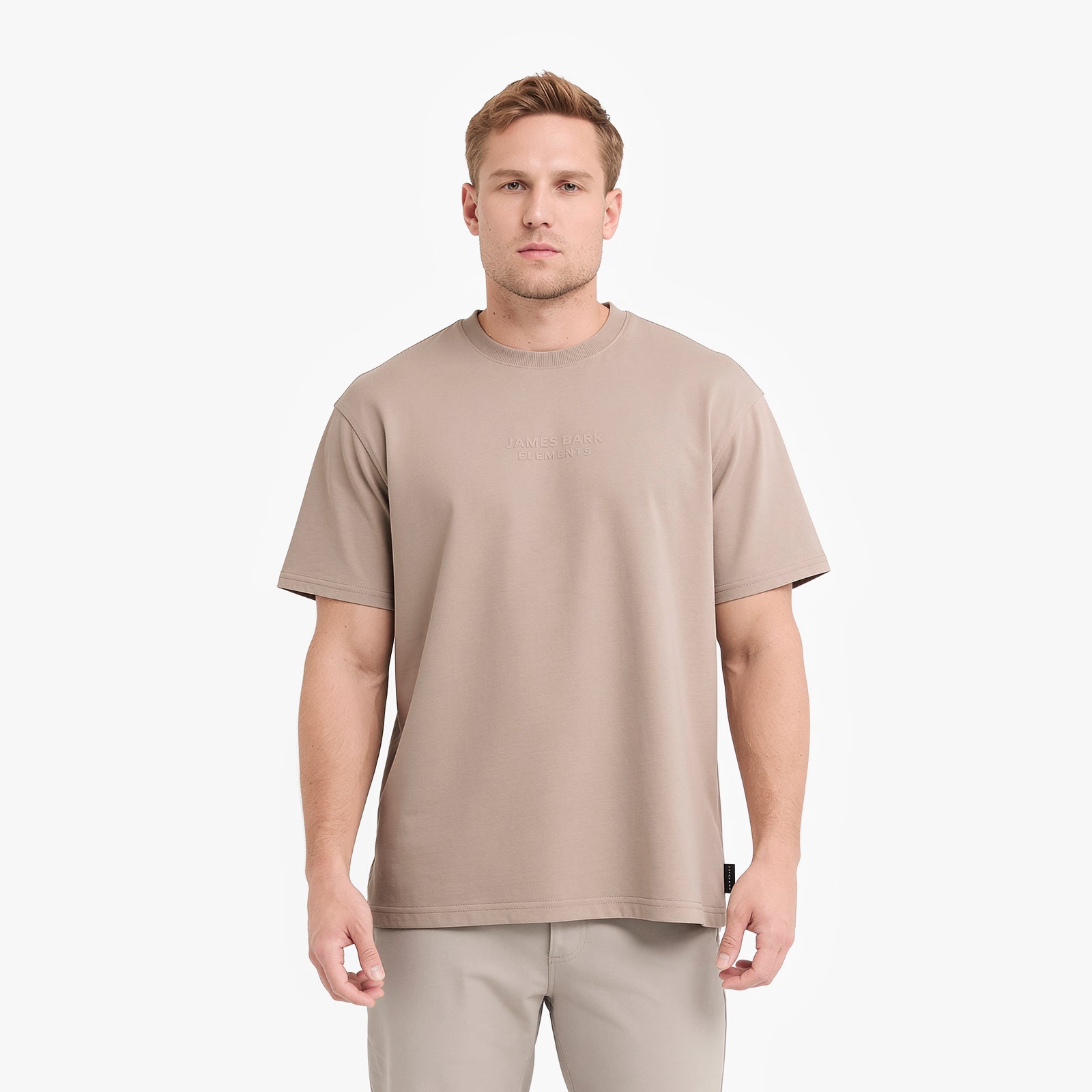 A man wearing a light taupe t-shirt and matching trousers