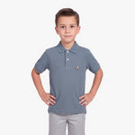 A young boy modeling a slate blue polo shirt with a small embroidered dog logo on the chest