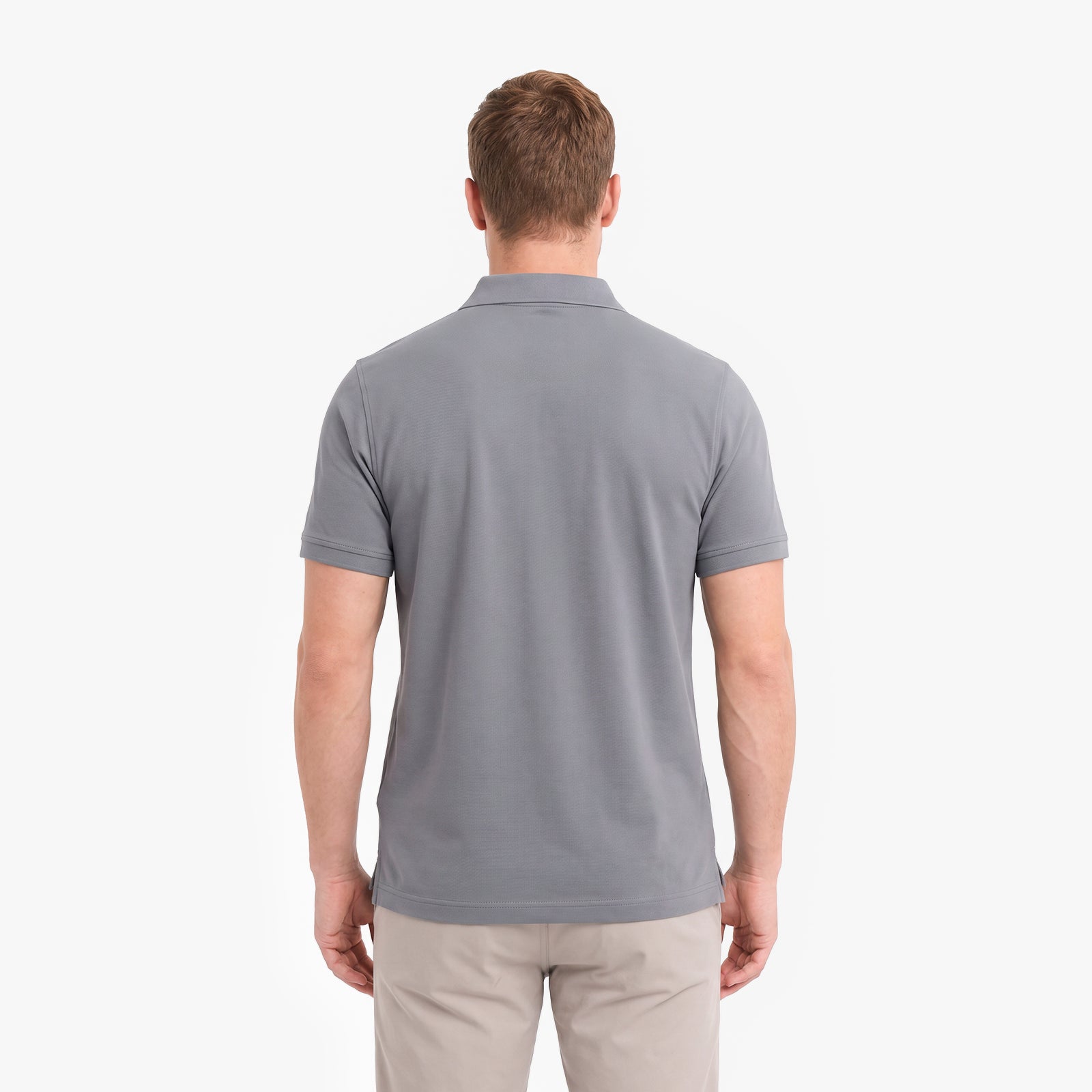 A man viewed from the back wearing a short-sleeve gray polo shirt and beige trousers.